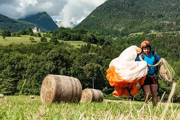 Un pilote de parapente volant au-dessus d'une montagne par temps clair, illustrant les conseils pour choisir le bon parapente.