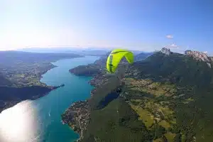 Vue aérienne du Lac d'Annecy entouré de montagnes et d'activités nautiques.