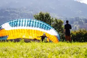 Élèves en formation de parapente apprenant à gonfler leurs ailes au sol.