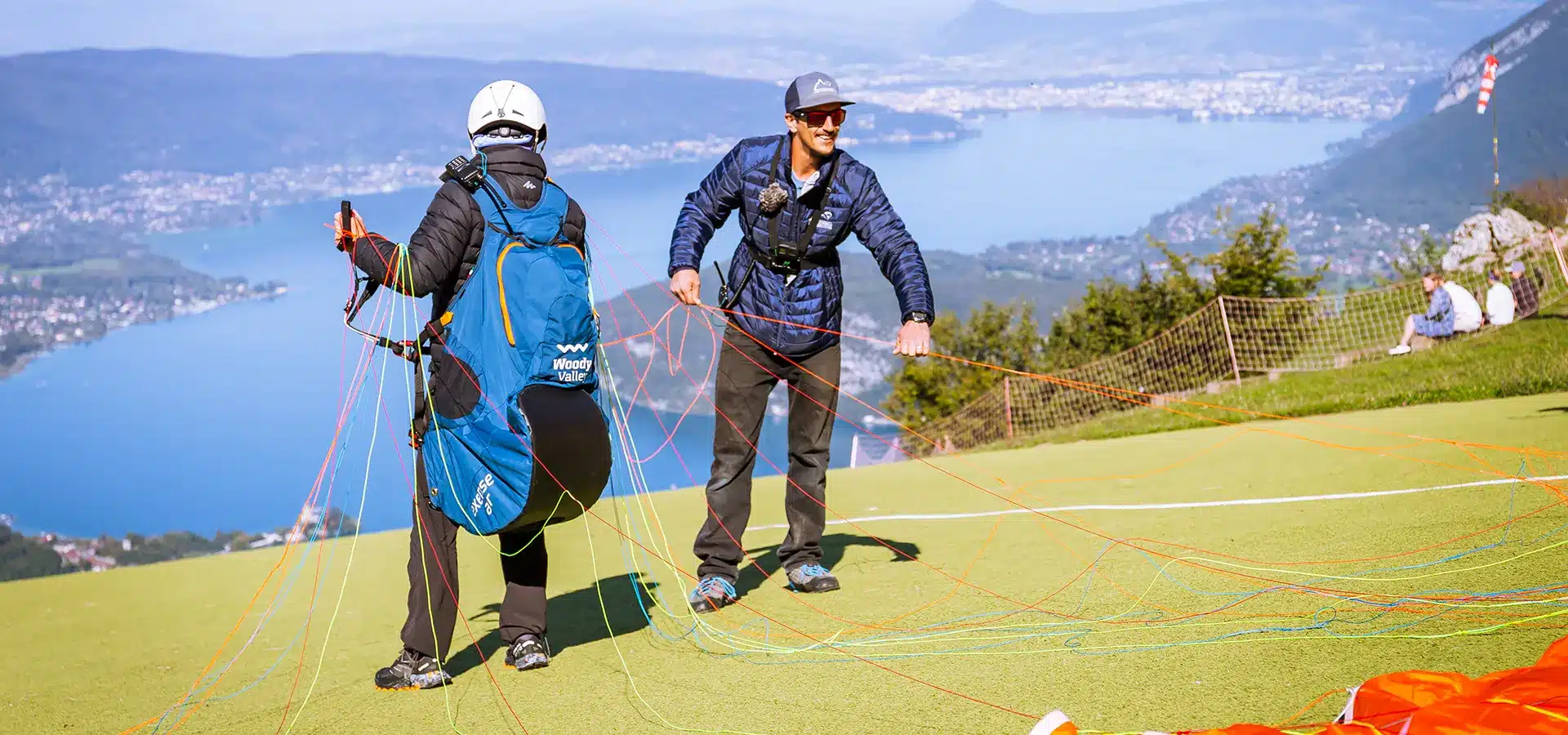 Groupe de stagiaires et moniteurs Aerodream partageant un bilan technique convivial après une séance de vol à Annecy.
